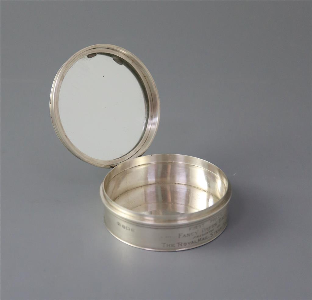A George V silver circular box and hinged cover, embossed with a ship and dancing figures above,